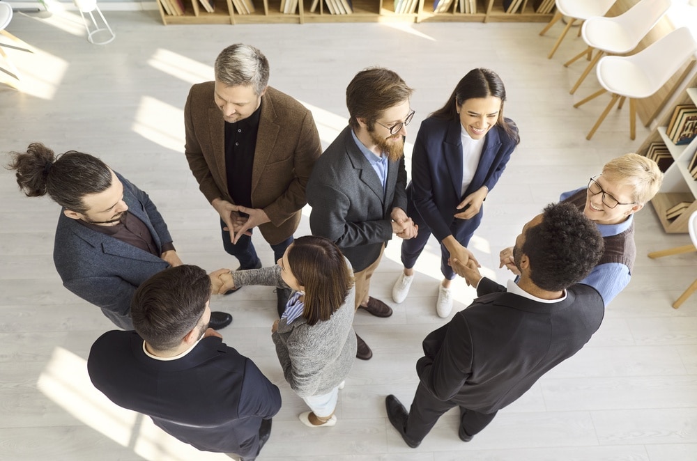 Business,People,Team,Meeting,With,Handshake,In,Office.,Top,View